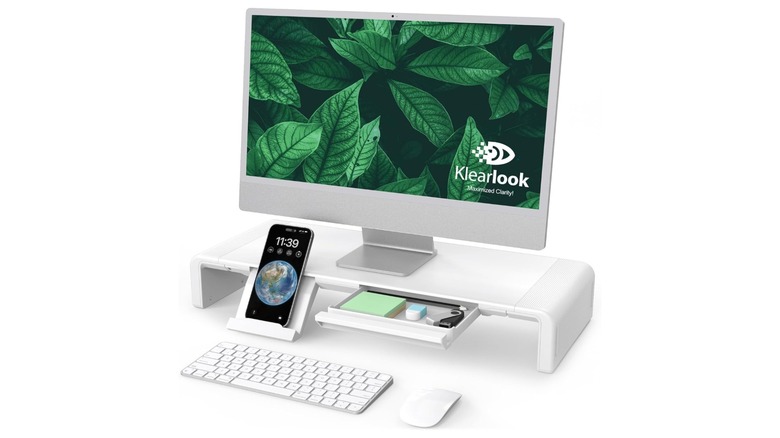 A promotional image for the Klearlook Adjustable Monitor Stand. The stand is holding a monitor and shows several items in its drawers.