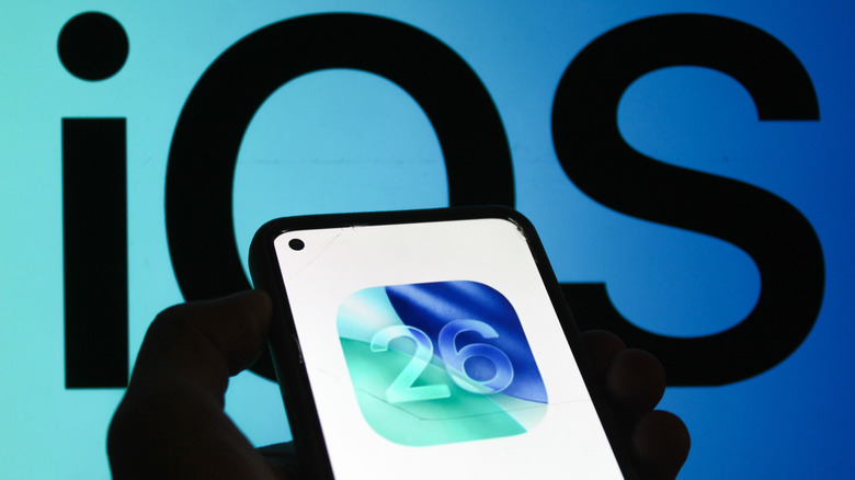 iOS 26 icon on a smartphone behind iOS logo