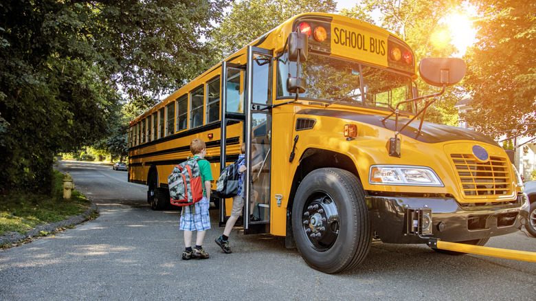 Kids getting on a school bus.