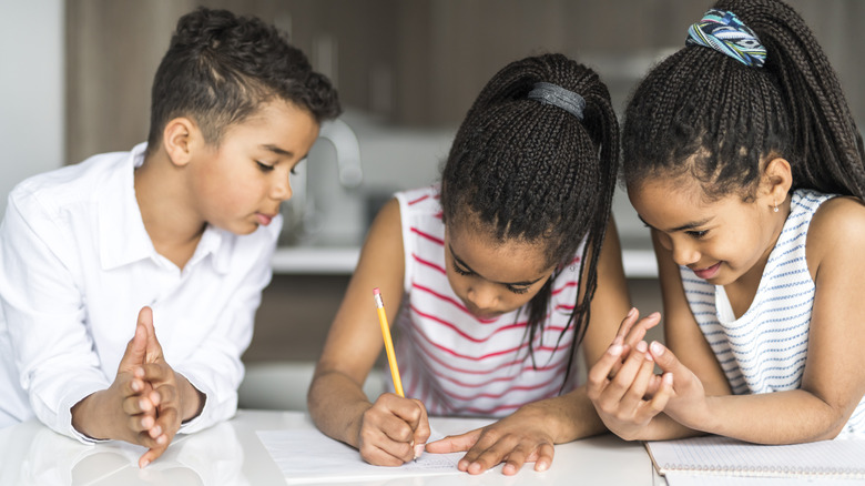 three kids working on schoolwork