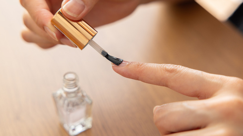 Close up of someone applying clear nail polish.