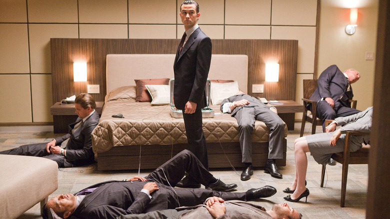 Arthur standing in a bedroom among unconscious men in Inception (2010)