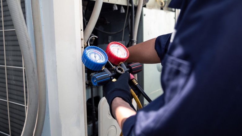 HVAC professional checking refrigerant levels in system with gauges.