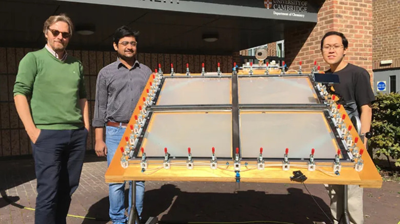 Scientists stand beside a large photocatalytic solar panel reactor