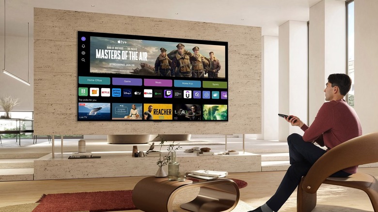 Man pointing remote at wall-mounted LG TV showing home screen