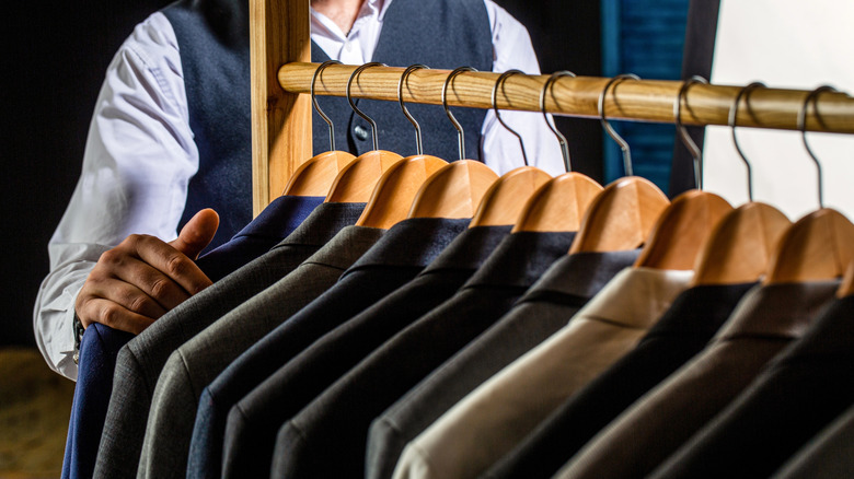 A man standing before a wooden rack of different colored jackets
