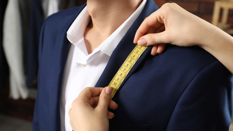 A woman's hands using a measuring tape to measure a man's chest