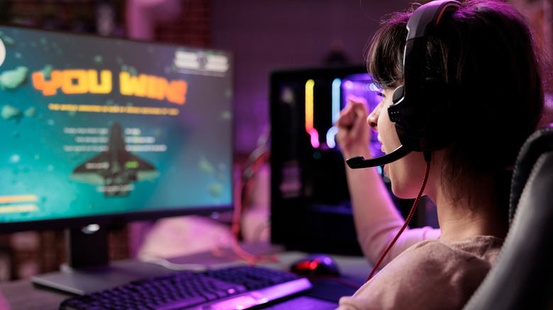 a girl with a headset on next to a monitor that displays 