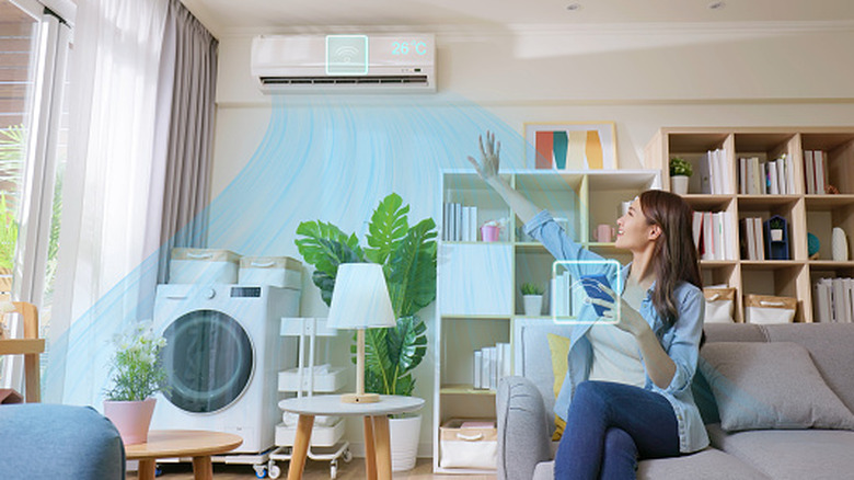 Person holding their hand up to a smart air conditioner controlled via their phone
