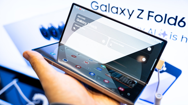 A Galaxy Z Fold 6 held in a person's hand in front of a display