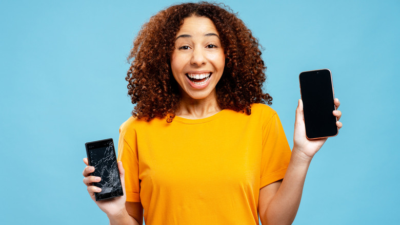 a woman holding two phones in her hand with one that has a broken screen and other is new