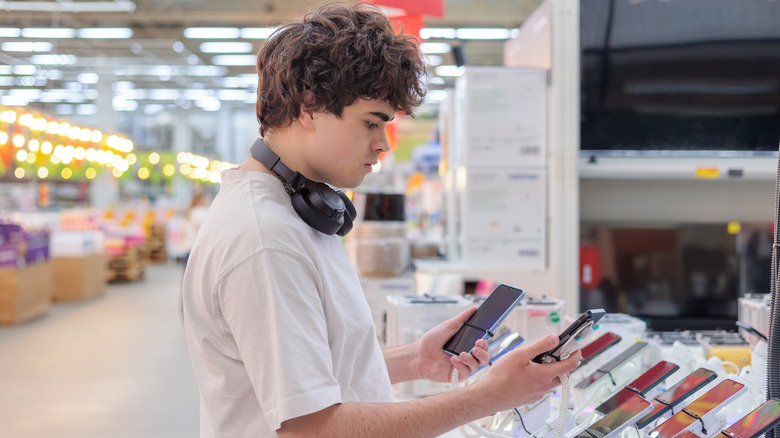 a man trying to find a new smartphone to buy at a retail electronics store