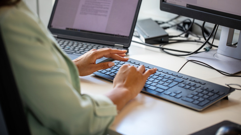 A woman typing on a computer keyboard.