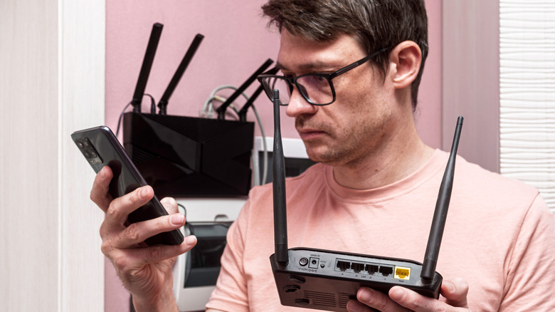 Man holding a Wi-Fi router with vertical antennas