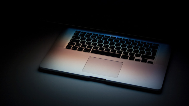 A laptop keyboard in view in a dark setting.