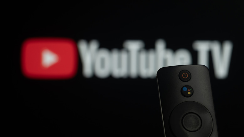 YouTube TV logo blurred in the background with Google Voice remote in view.