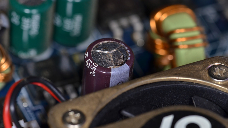 A close-up of a failed or damaged electrolytic capacitor on a computer motherboard.