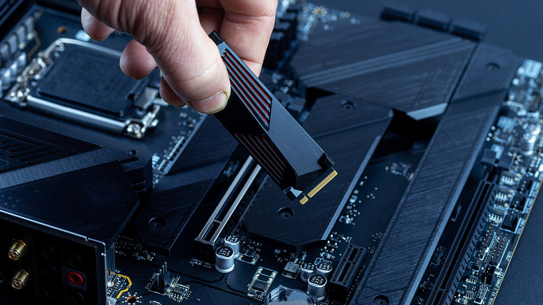 A person installing or removing an M.2 NVMe SSD from a desktop motherboard.