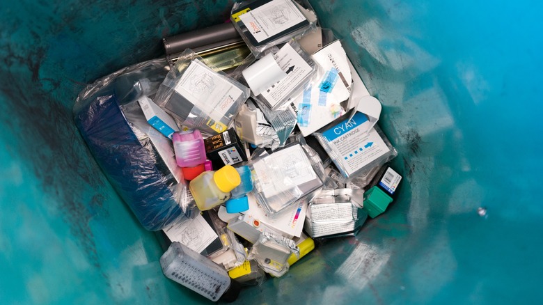 Many discarded single-use printer cartridges piled up in the trash