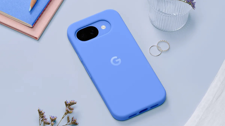 Pixel 10a with blue case sitting face down on blue desk showing G logo on back