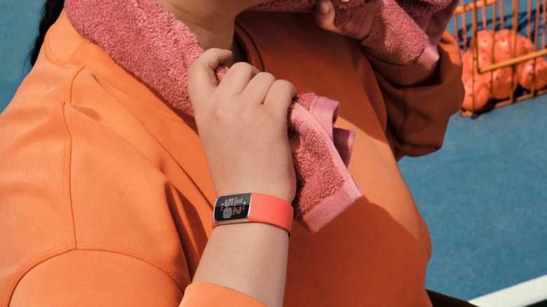 The wrist of a woman drying off with a towel wearing the Fitbit Charge 6.