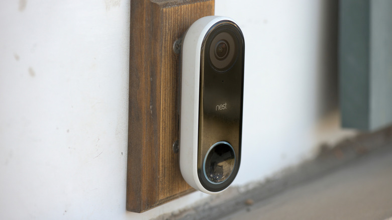 A Nest video doorbell mounted to a piece of wood