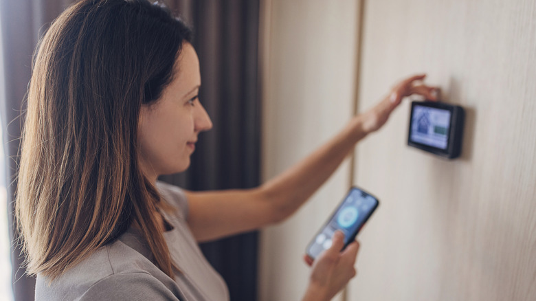 A person using their phone and their thermostat in tandem