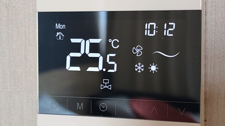A digital thermostat on the wall of a home