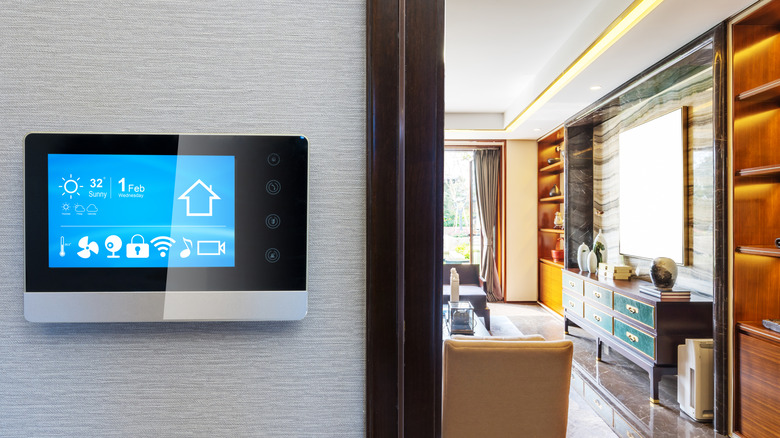 A digital smart thermostat placed on a wall of a house, with the kitchen in full view