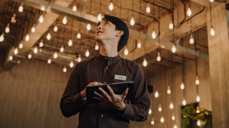 Person using a tablet to manage lighting in a smart home environment