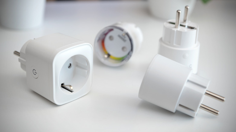 Smart plug and European power adapters placed on white surface