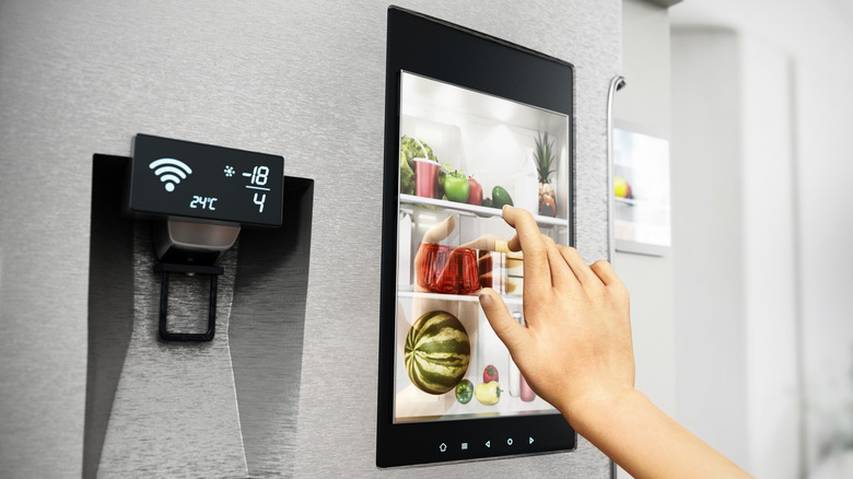 A hand touching the interface of a smart refrigerator