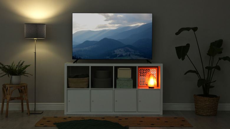 Living room TV with lighting nearby and outdoor scenery on screen.