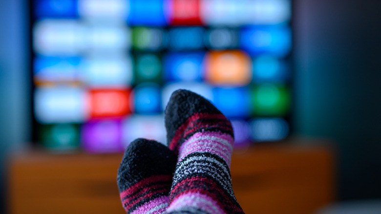Socks in foreground with blurred smart TV in background and app menu visible.