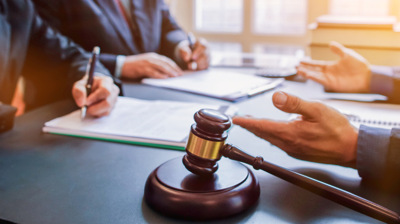 Judge gavel on table in front of businessmen.