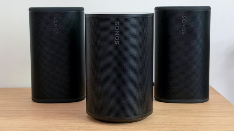 Sonos Era 100 SL with a pair of Sonos Play speakers on the background