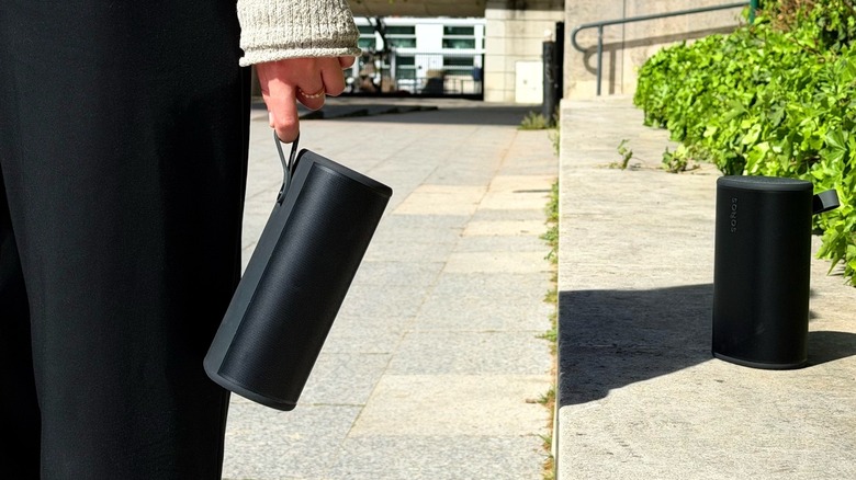 A girl holds a Sono Play speaker while another one is on the background