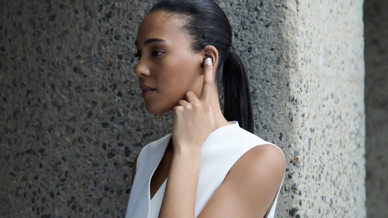 A woman presses with her finger Sony's WF-1000XM6 earbuds