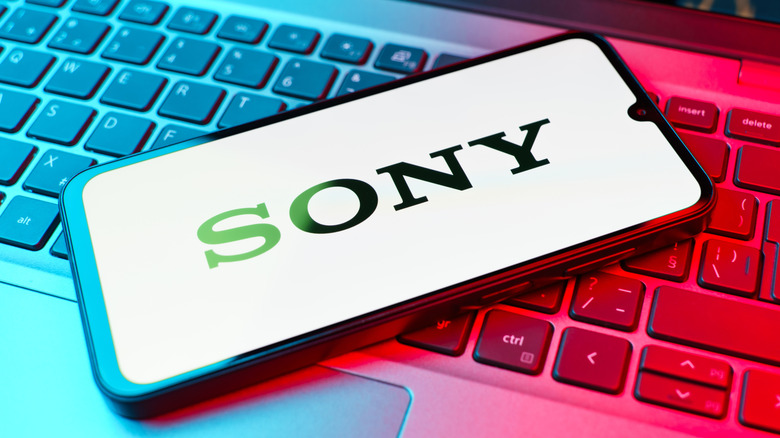 A smartphone displaying the Sony logo as it lays on a laptop keyboard, the keyboard is adorned in blue and red light