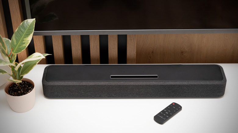 Soundbar and remote resting on a desk next to a potted plant
