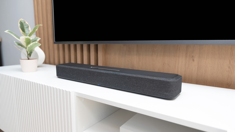 A soundbar placed below a wall-mounted TV in a modern living room.