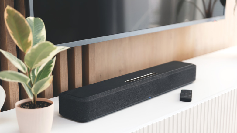 A soundbar with remote on a mantle below of a mountain flat screen television