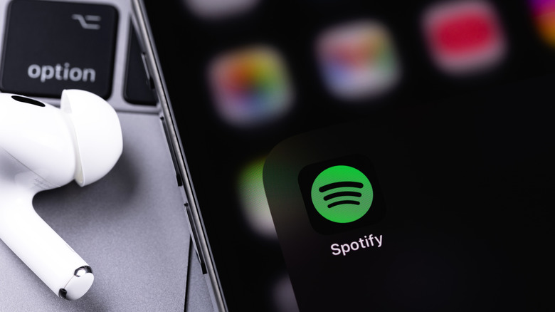 Spotify app icon on a smartphone with macbook keyboard in background
