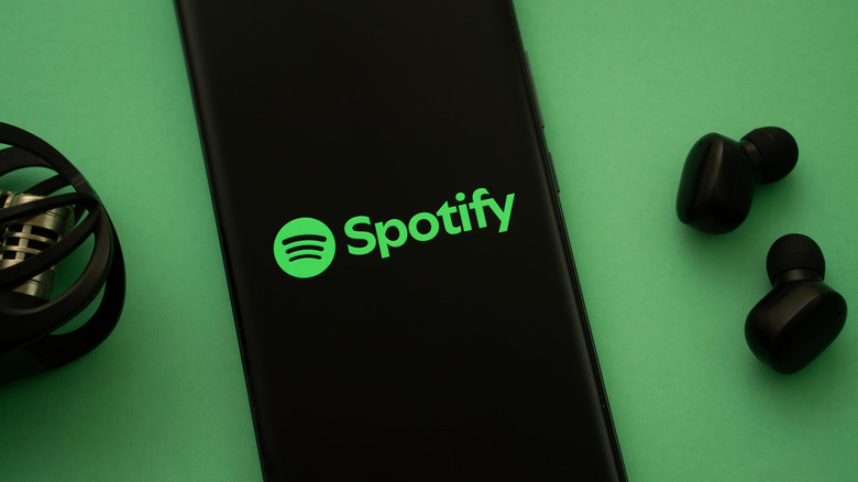 Spotify logo displayed on a smartphone screen lying on a green background