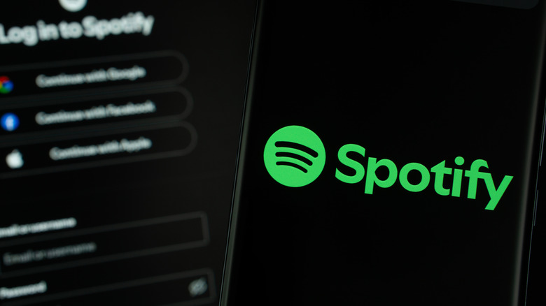 Spotify logo on a smartphone with spotify's login screen in the background