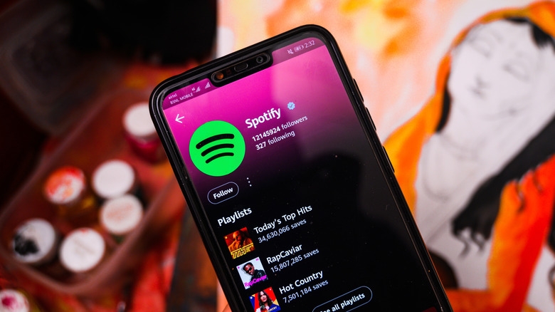 Spotify profile pulled up on a smartphone in front of posters and paint cans