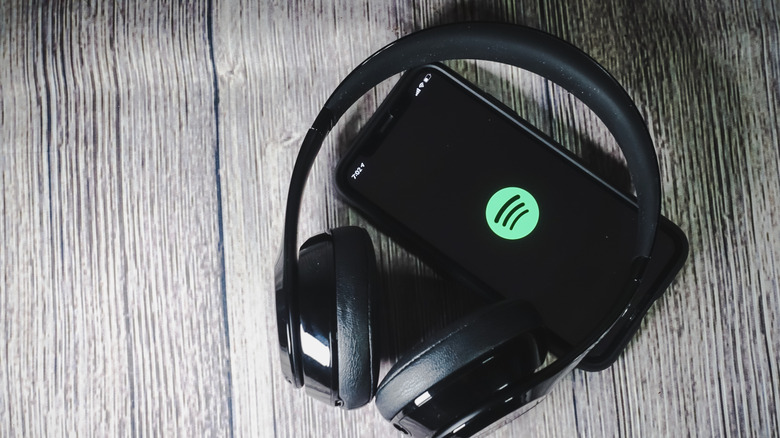 spotify logo on a phone with headphones on top of it