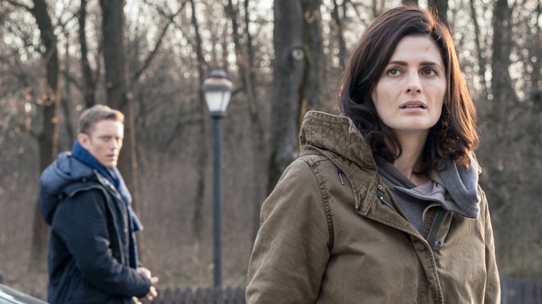 Stana Katic as Emily Byrne stood near a treeline with Neil Jackson as Jack Byrne in Absentia