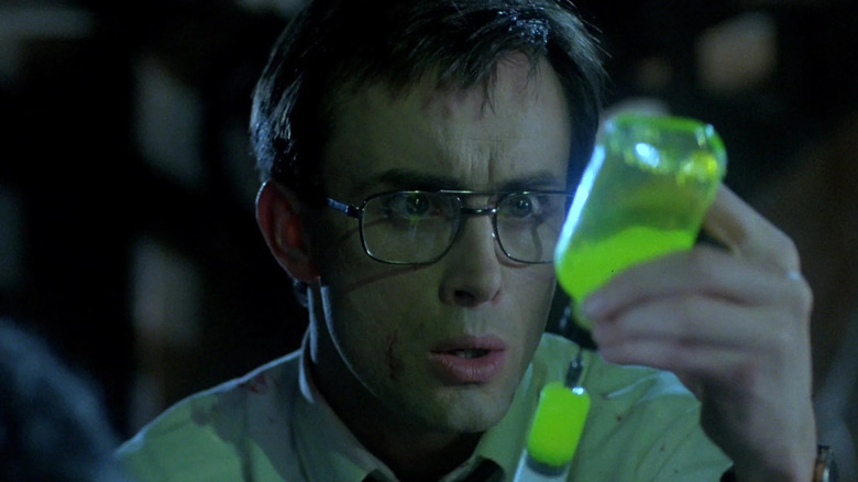 Herbert West (Jeffrey Combs) holding a syringe in 