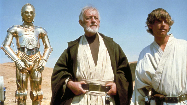 C-3PO, Ben Kenobi, and Luke Skywalker look over Mos Eisley in a scene from Star Wars